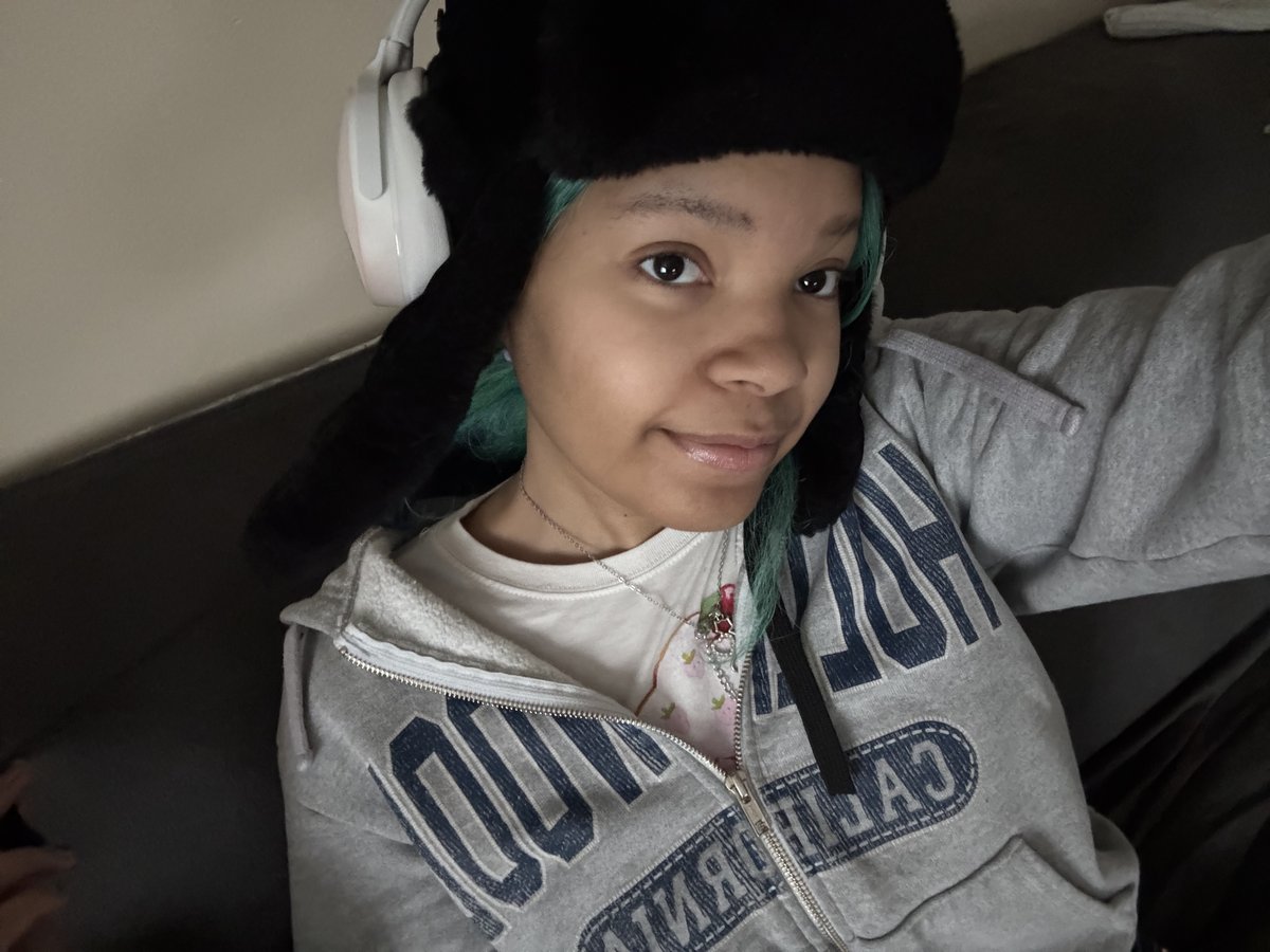 mya wearing a black ushanka hat with green hair